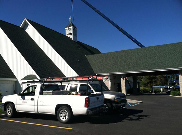 A mobile crane lifts the replacement cupola into place atop Park Heights Church