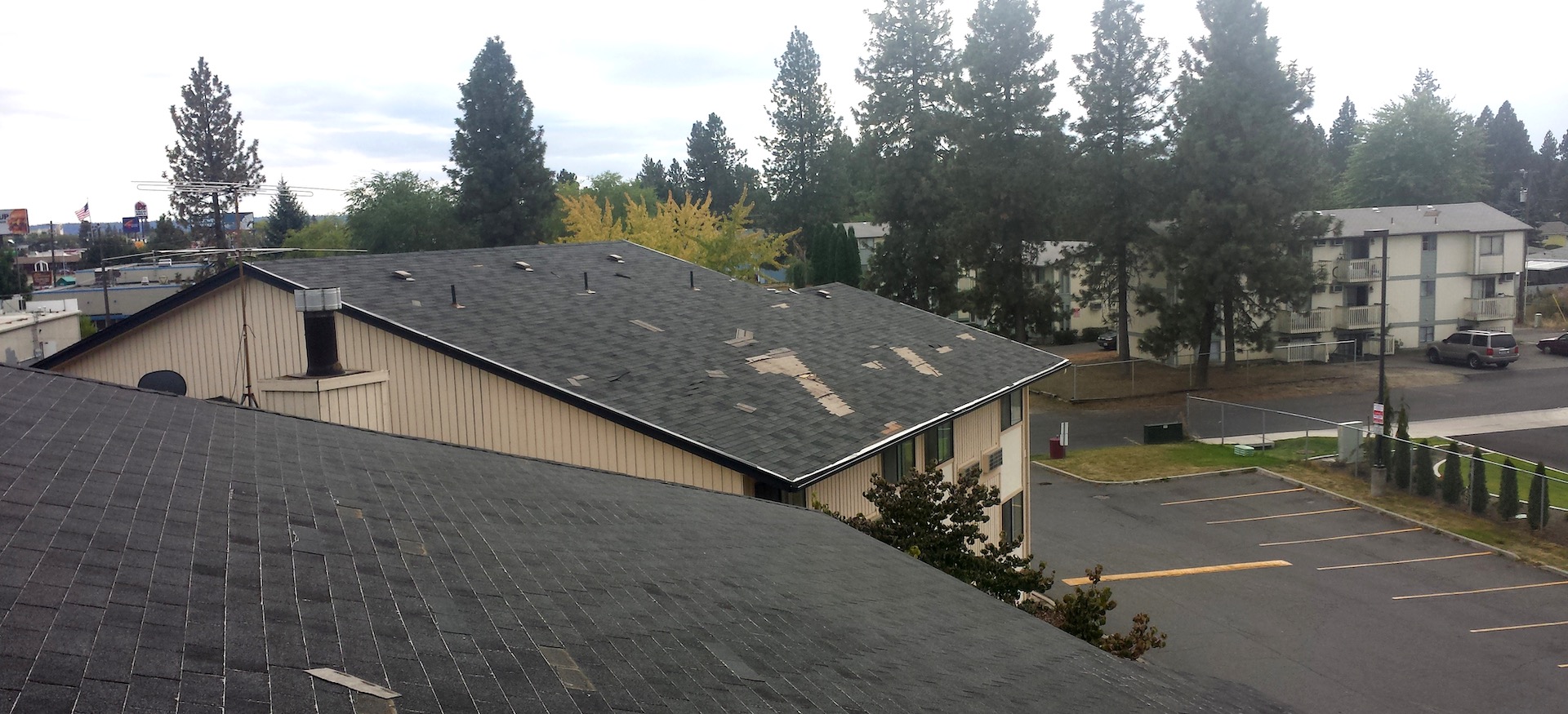 Windstorm Apartment Roof Damage - Roofing Shingles Unzipped And Blown About