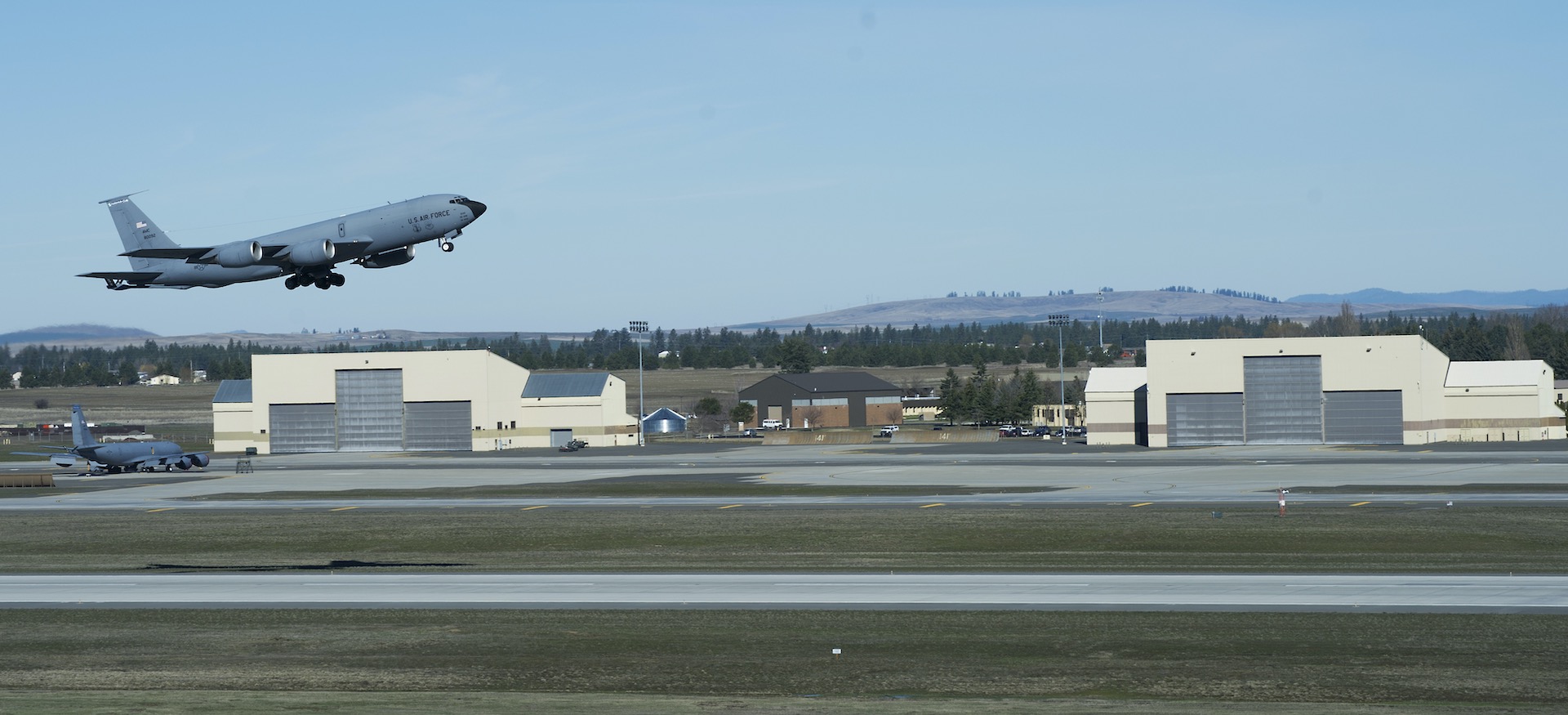 Fairchild AFB refueling tanker during takeoff with hangers in background